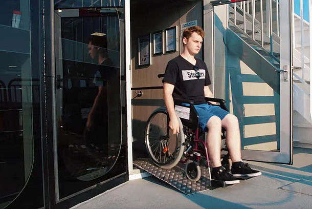 Ein Passagier, im Rollstuhl, nutz eine Rollstuhlrampe auf dem "Halunder jet".
